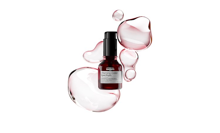 Packshot of Vitamino Color Spectrum Hair Serum for colored hair, surrounded by textured drops of serum highlighting its rich formula.