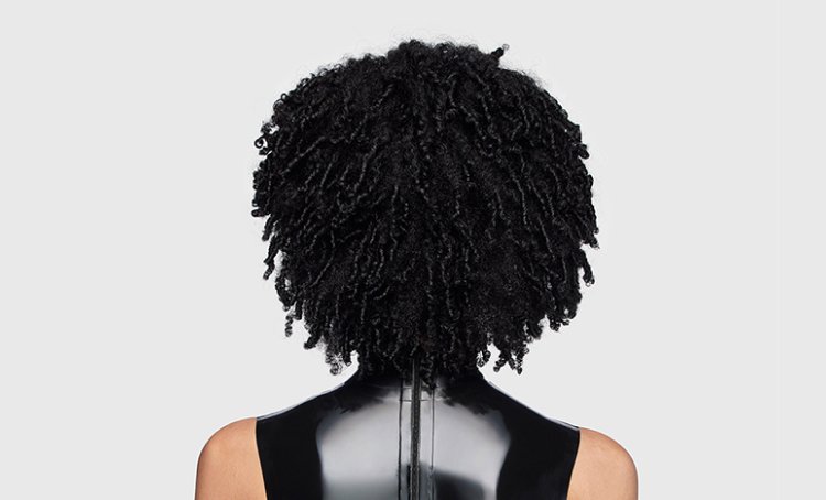 Woman from behind with shiny, healthy defined curls, illustrating tips and care techniques to maintain nourished, coily hair.​
